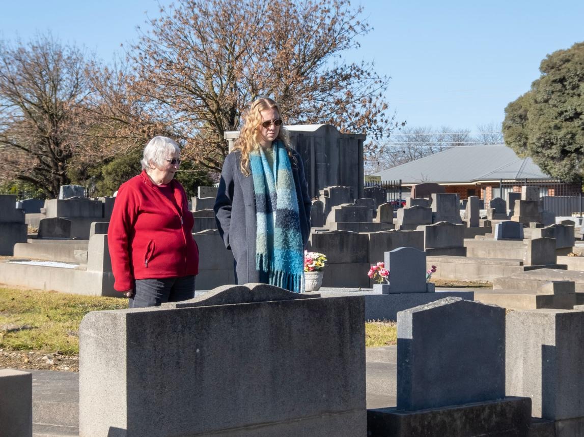 Senior and caregiver visiting a cemetery memorial